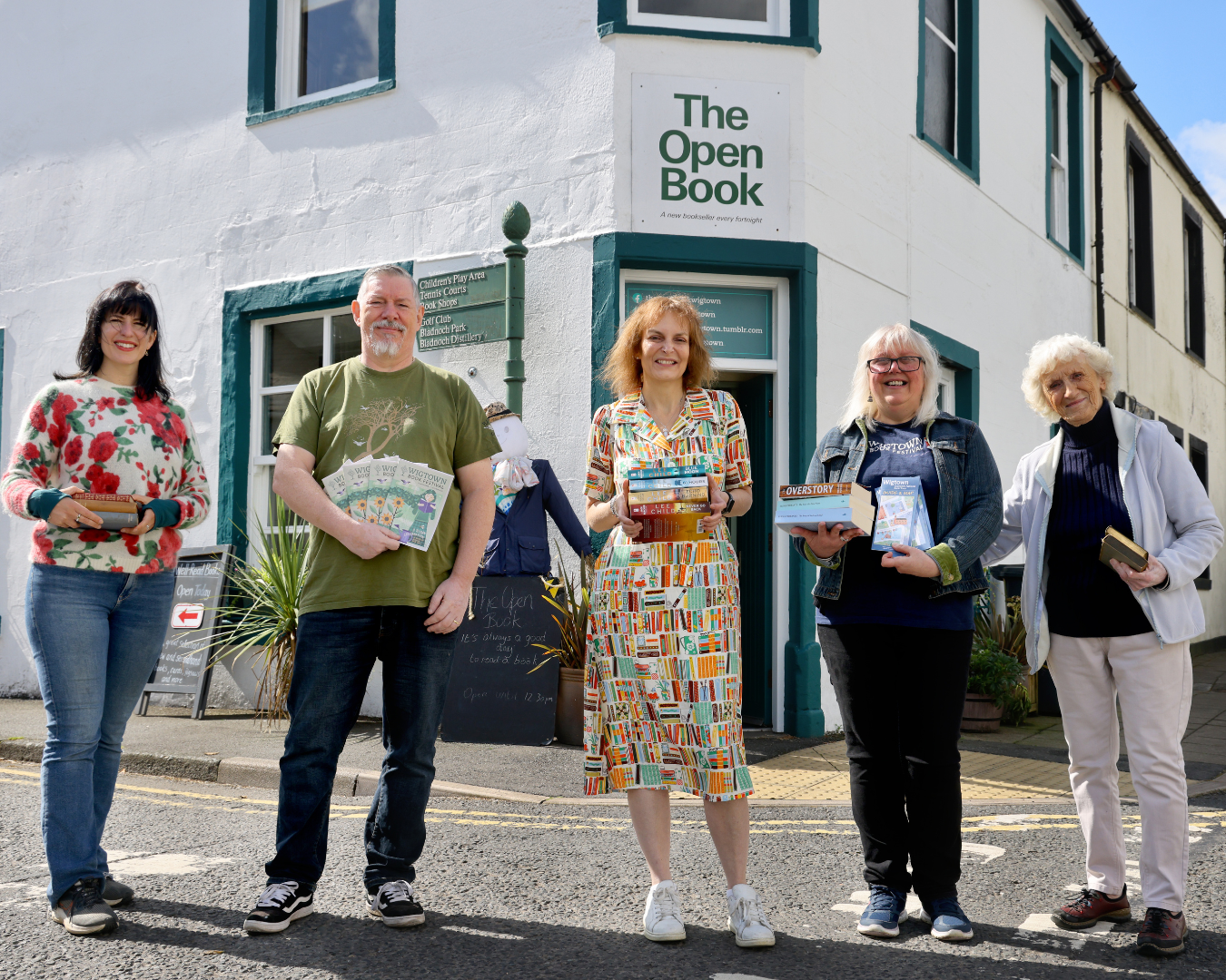 Five guests and volunteers stood in front of The Open Book, holding books and festival programmes.