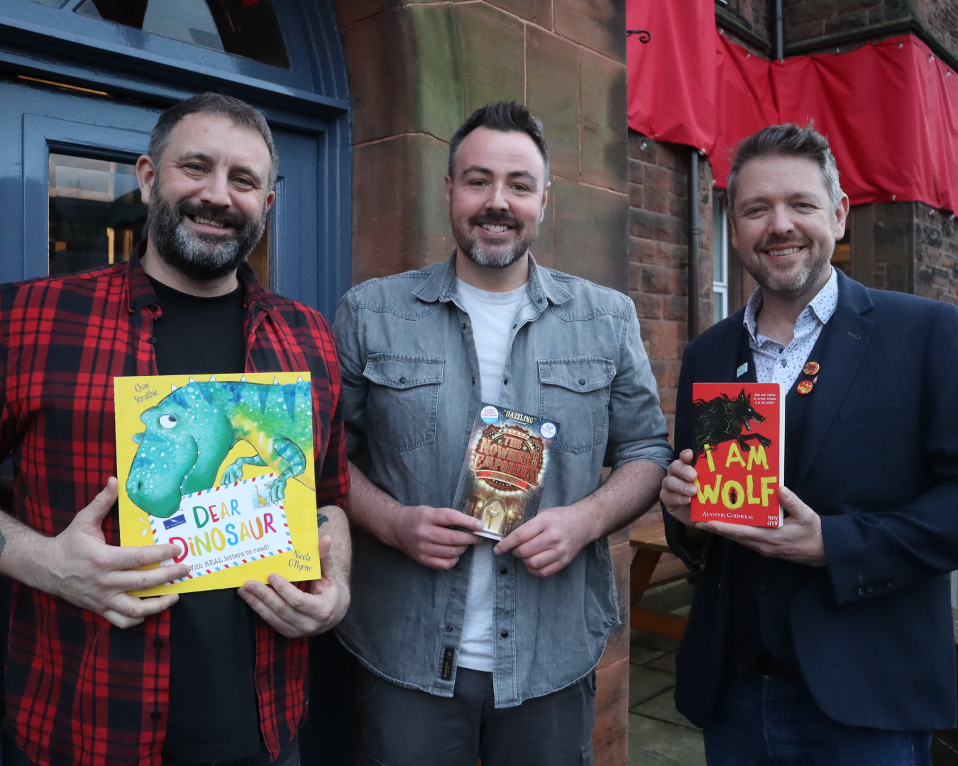 Portrait of Chae Strathie, Ross MacKenzie and Alastair Chisholm holding books, as part of the Big DoG Schools Tour