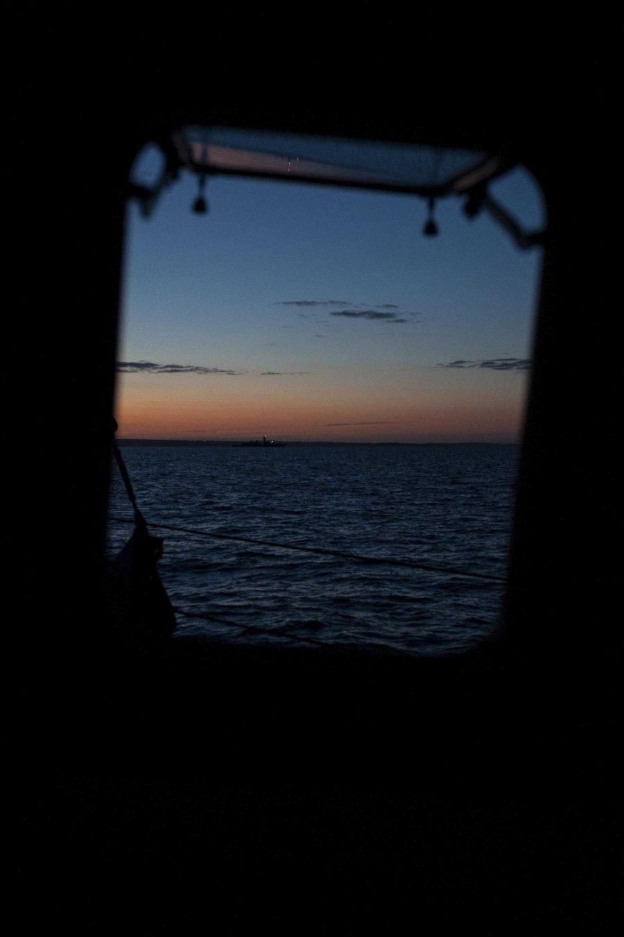 Looking out of a window on a fishing boat as the sun is setting.