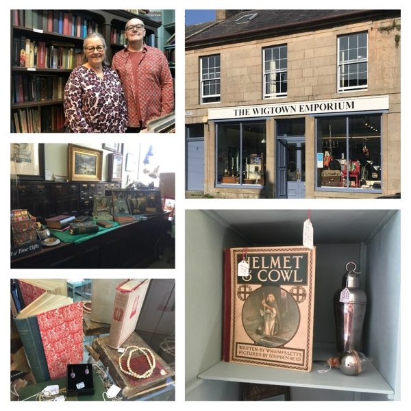 The Wigtown Emporium. A stone clad building with large shop windows and the sign above. John and Sara Black stands in front of a bookshelf. Various items for sale within their shop.