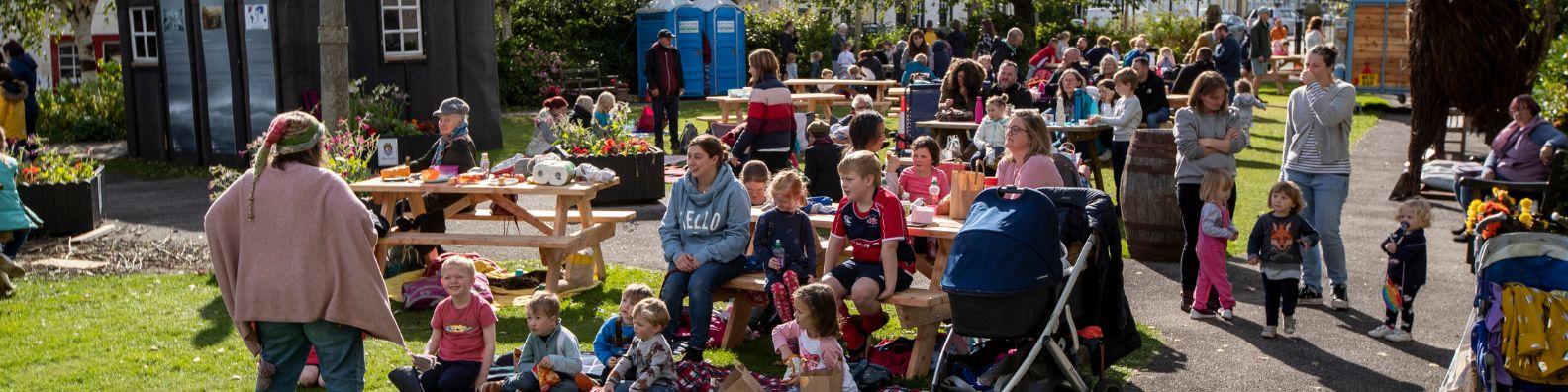 Outdoor children's event during Wigtown Book Festival. Families with young children sit in the garden as they are entertained by Renita Boyle.