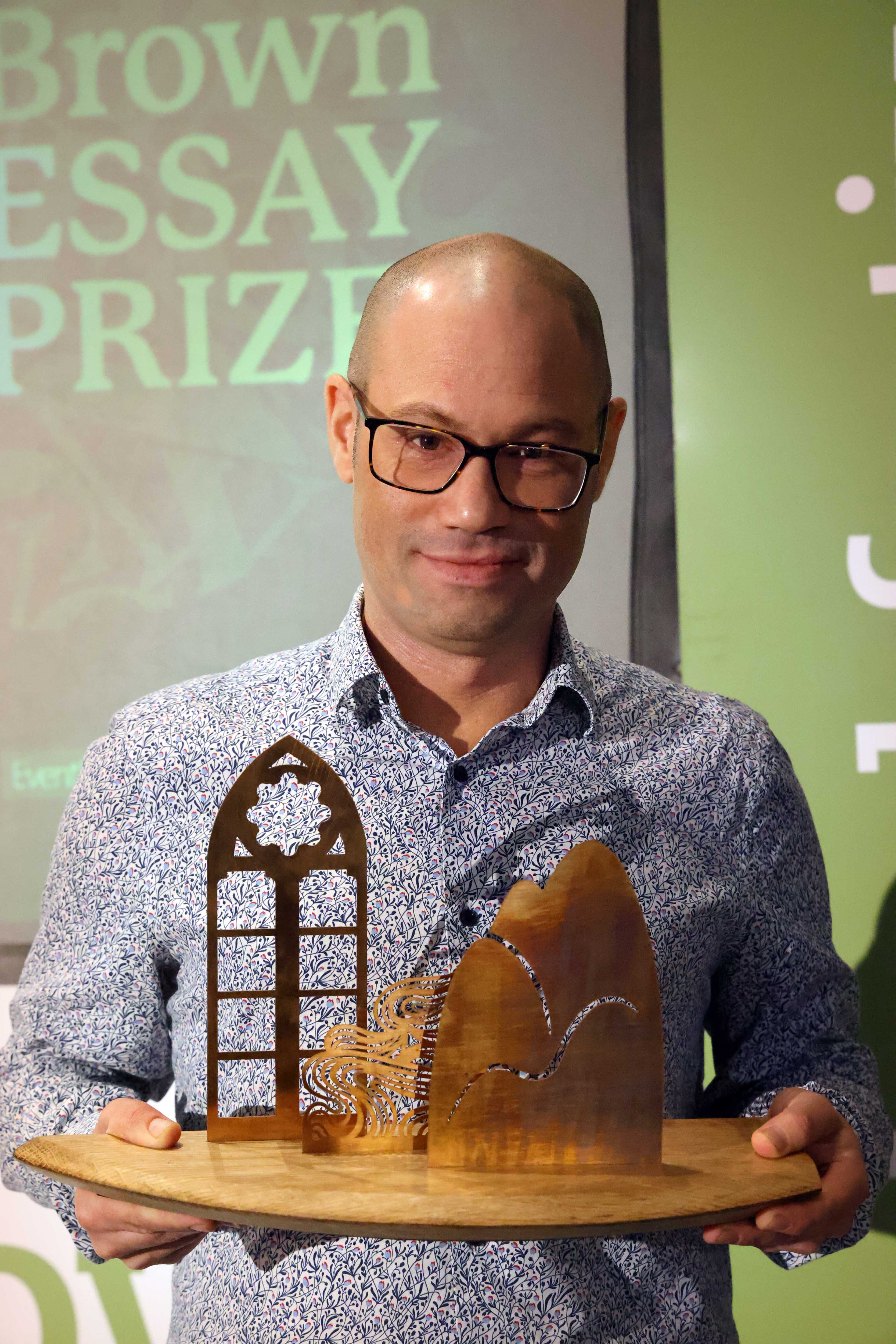 Author Rodge Glass holds the Anne Brown Essay Prize trophy.
