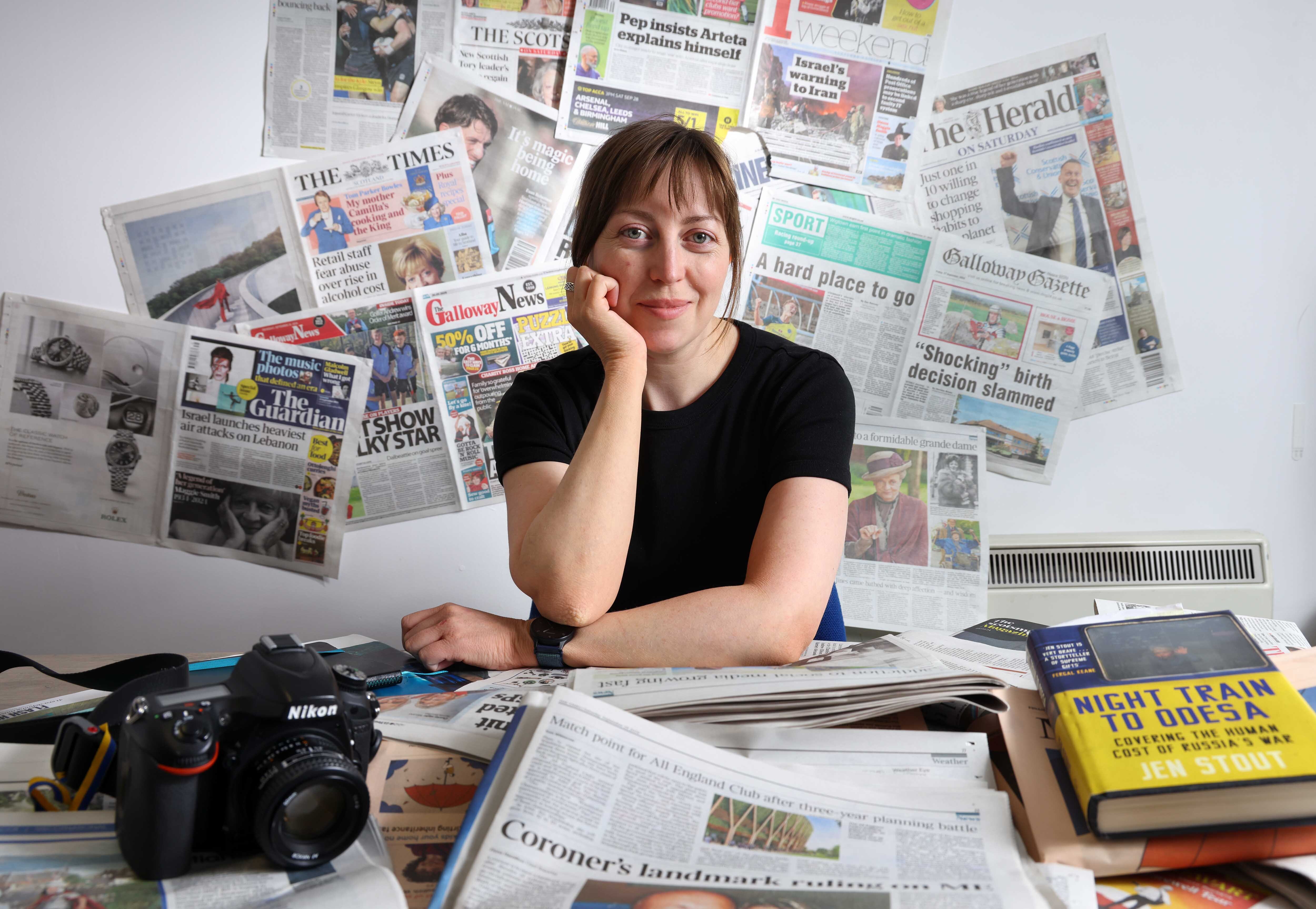 Portrait of Foreign Correspondent Jen Stout surrounded by newspapers