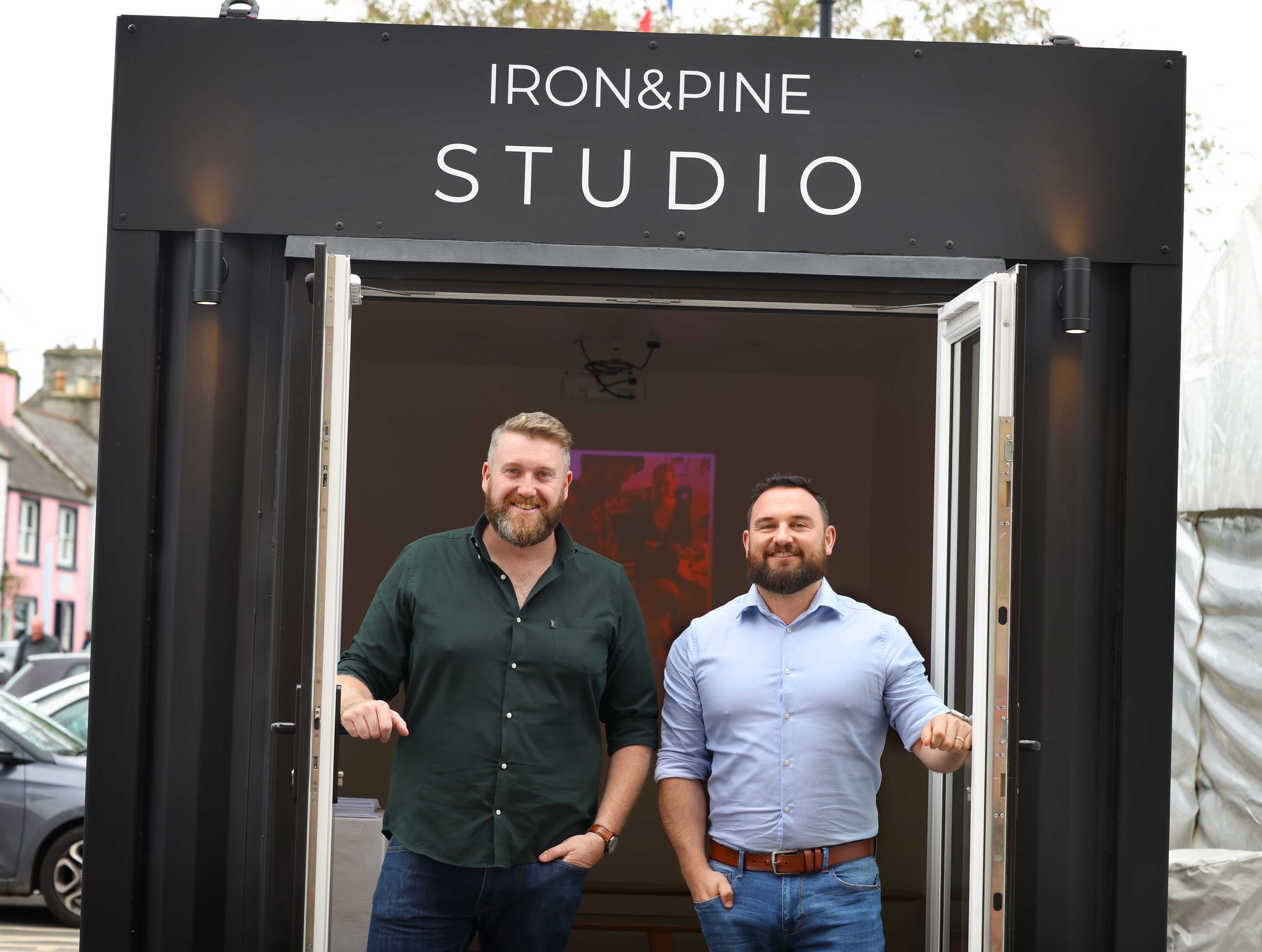 Two Iron and Pine executives stood outside the 25th festival photo exhibition, created from a shipping container.