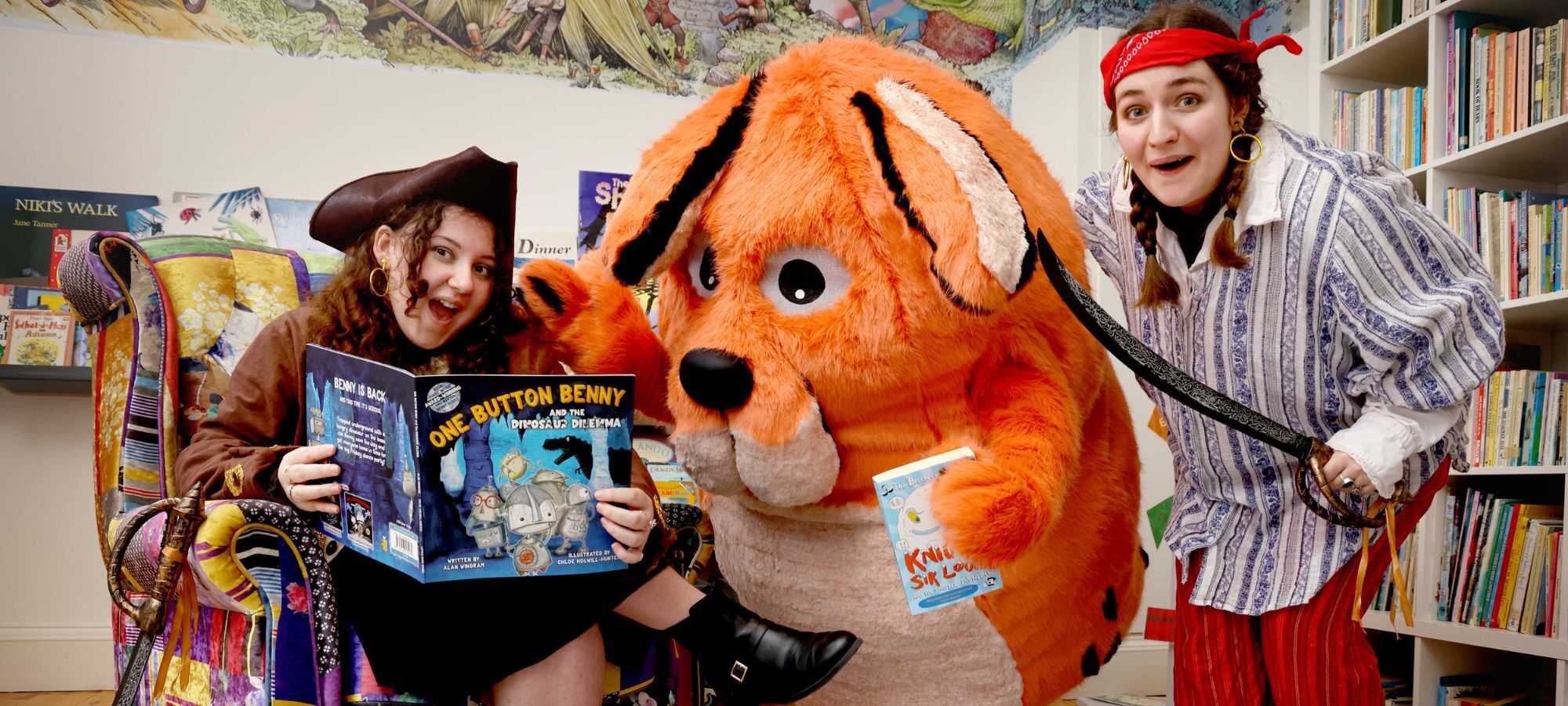 Two Moat Brae storyweavers are dressed as pirates, either side of Big DoG mascot; a large, orange dog.