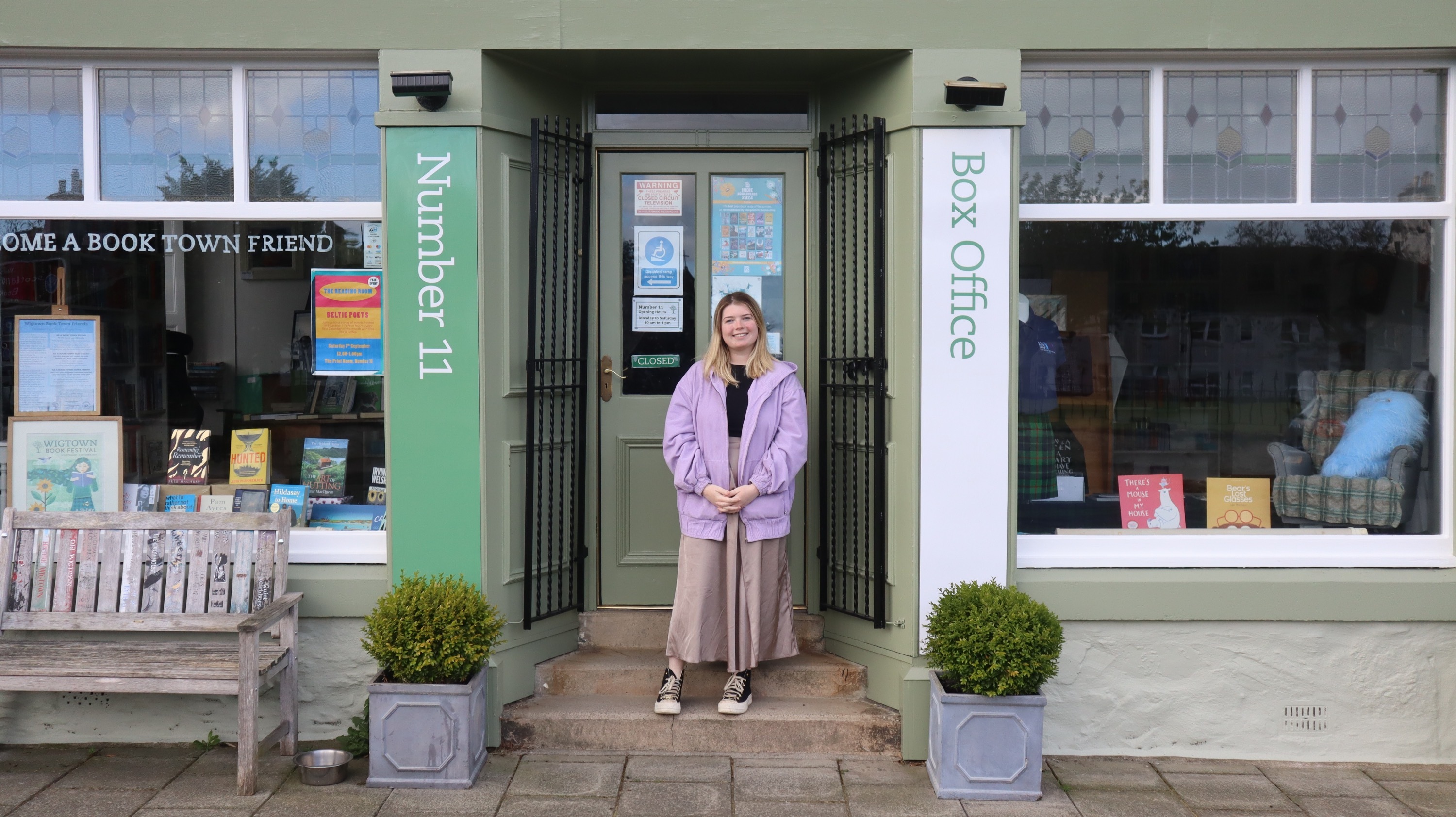 Youth Engagement Officer Morgan Love stood in front of Number 11 Bookshop, wide shot centred between two columns.