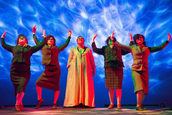 Shuna Scott Sendall and Scottish Operas Connect Chorus in Dido and Aeneas Scottish Opera 2017. The principal is wearing a long gown with others dancing with raised arms beside her. Behind them blue and white flickering lights.