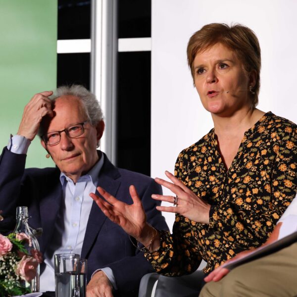Henry McLeish and Nicola Sturgeon seated on stage at Wigtown Book Festival. McLeish scratches his head, Sturgeon gestures with her hands while speaking.