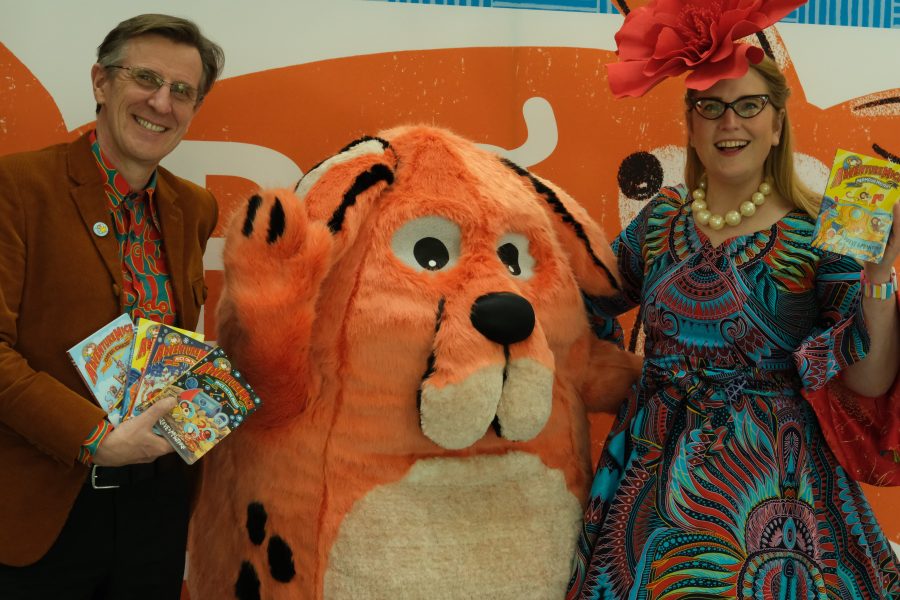 Philip Reeve and Sarah MacIntyre at the Big DoG Schools Gala Day. They are standing with Big Dog, holding books and smiling.