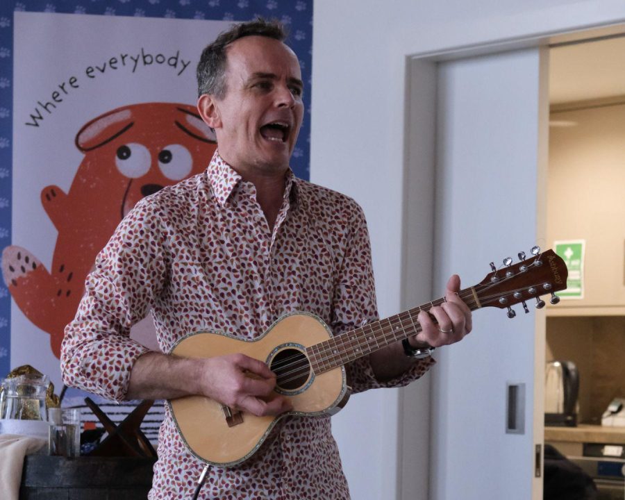 Gareth P Jones stands singing and playing a ukele at a Big Dog Children's Book Festival event.