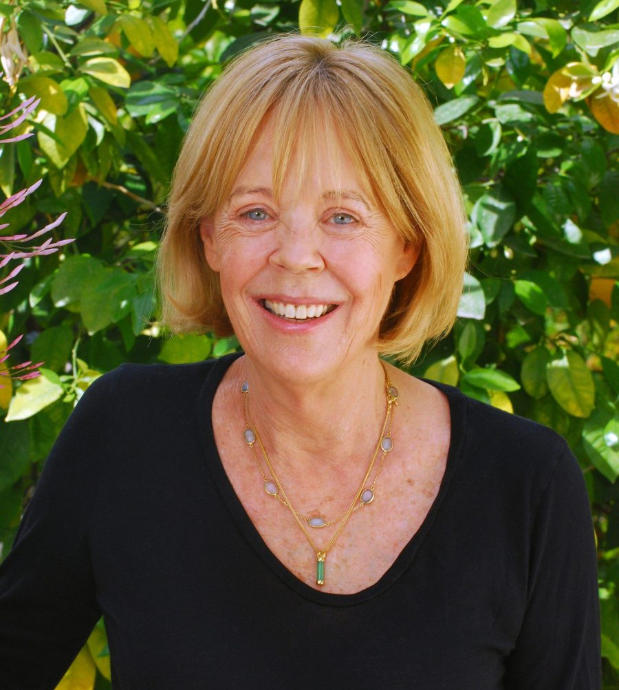 Headshot of Emma Soames standing in front of a green bush.