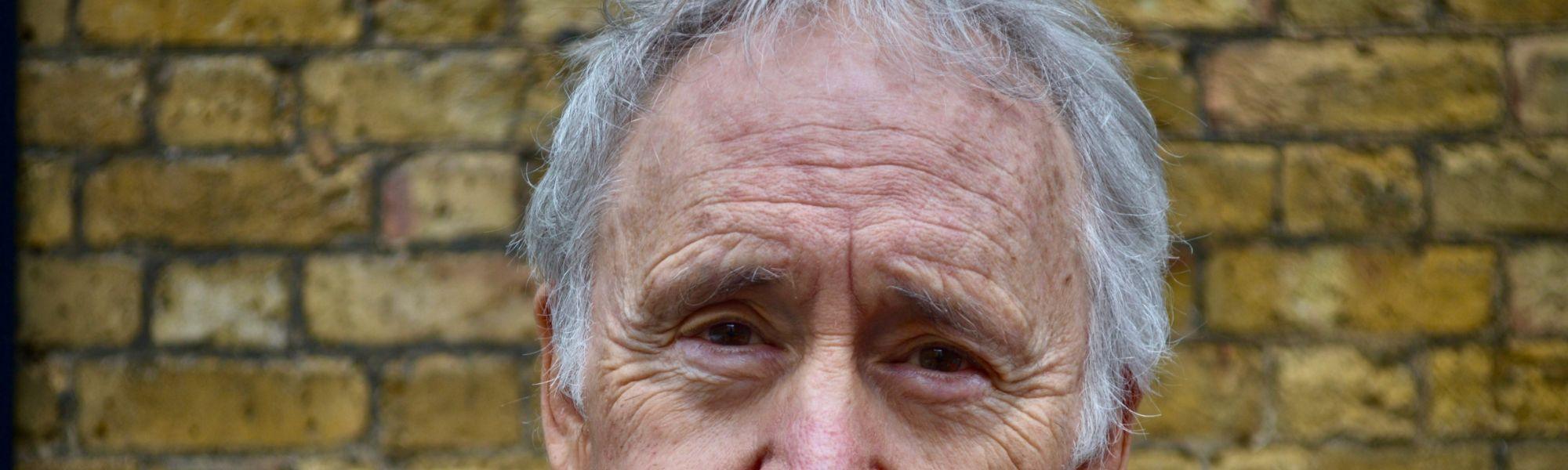 Headshot of Nigel Planer standing in front of a brick wall.