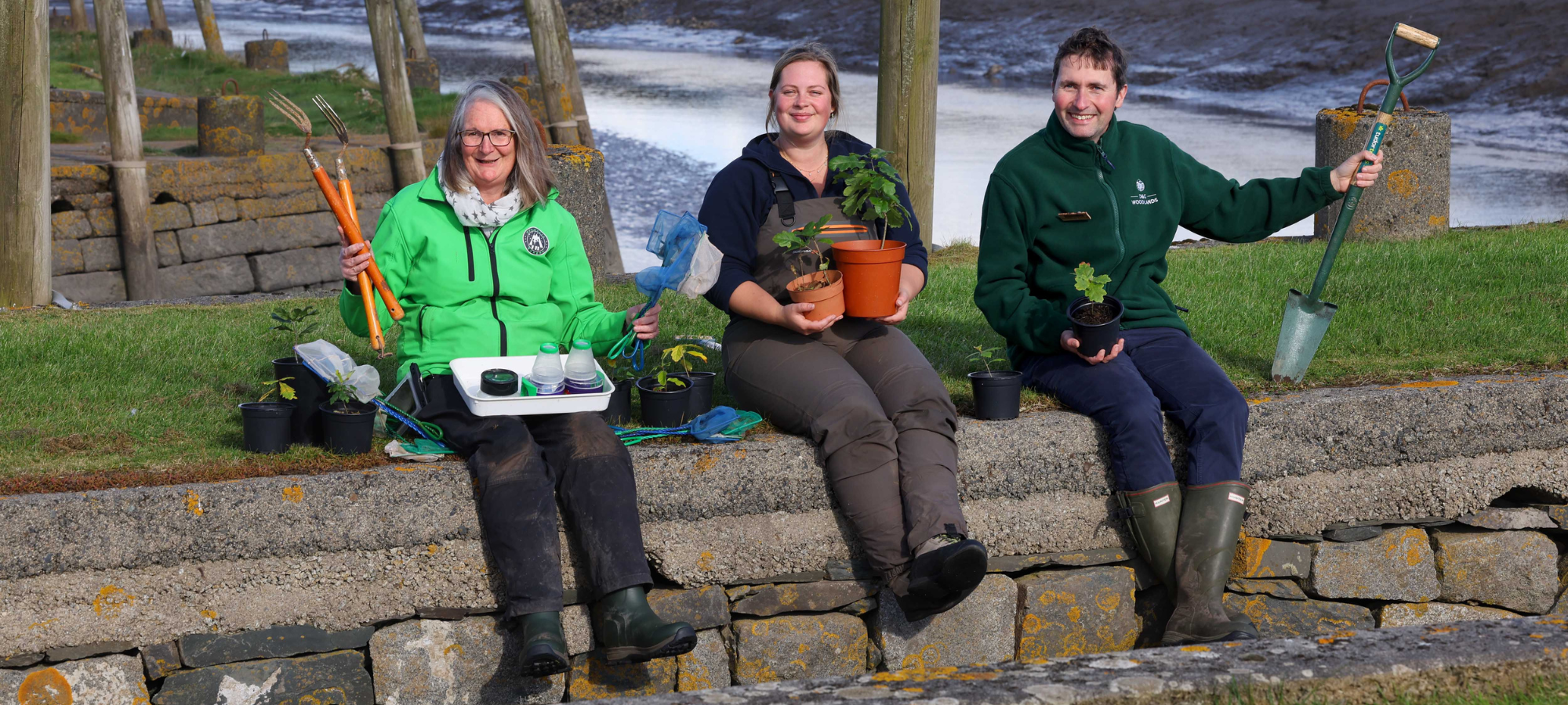 Three event guides for Wigtown Book Festival coastal fringe programme, sat on a wall by Wigtown Harbour.