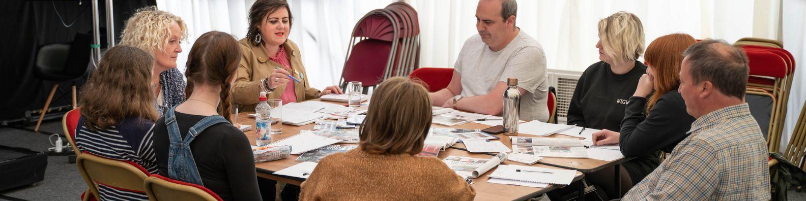 A young people's event at Wigtown Book Festival. Authors gather round a table with a group of young writers.